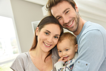 Wall Mural - Portrait of happy parents holding baby girl