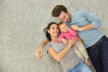 Wall Mural - Upper view of family of three laying on carpet