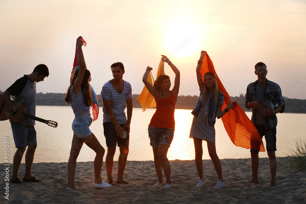 Carefree friends have fun on sunset near water