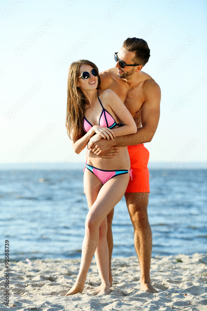 A guy hugging a girl at the beach, outdoors
