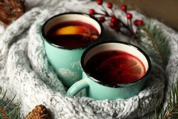 Poster - Decorated composition of mugs with mulled wine in knitted scarf, close up