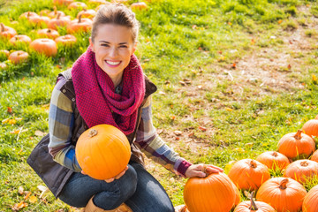 Wall Mural - Portrait of smiling woman holding pumpkins on farm