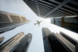 © Patrick Foto - Tall city buildings and a plane flying overhead