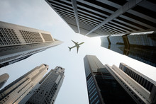 Tall City Buildings And A Plane Flying Overhead