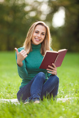 Wall Mural - Young woman is reading a book in park