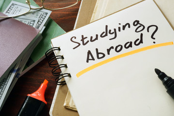 Notepad with Studying Abroad? on the wooden table.