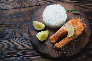 Wall Mural - Rustic wooden cutting board with roasted trout steak and rice