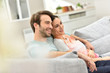 © goodluz - Couple relaxing in sofa and watching tv