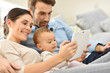 © goodluz - Parents with baby girl in sofa using digital tablet