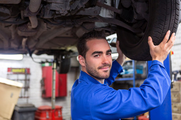 Wall Mural - Young attractive mechanic working on a car at the garage