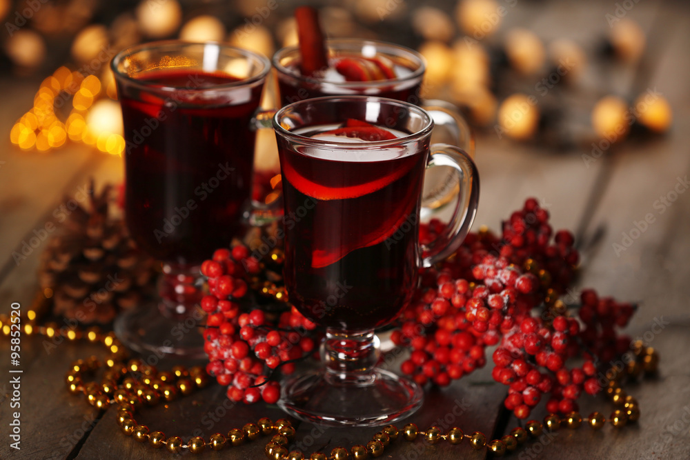 Mulled wine with spices and Christmas tree on wooden background