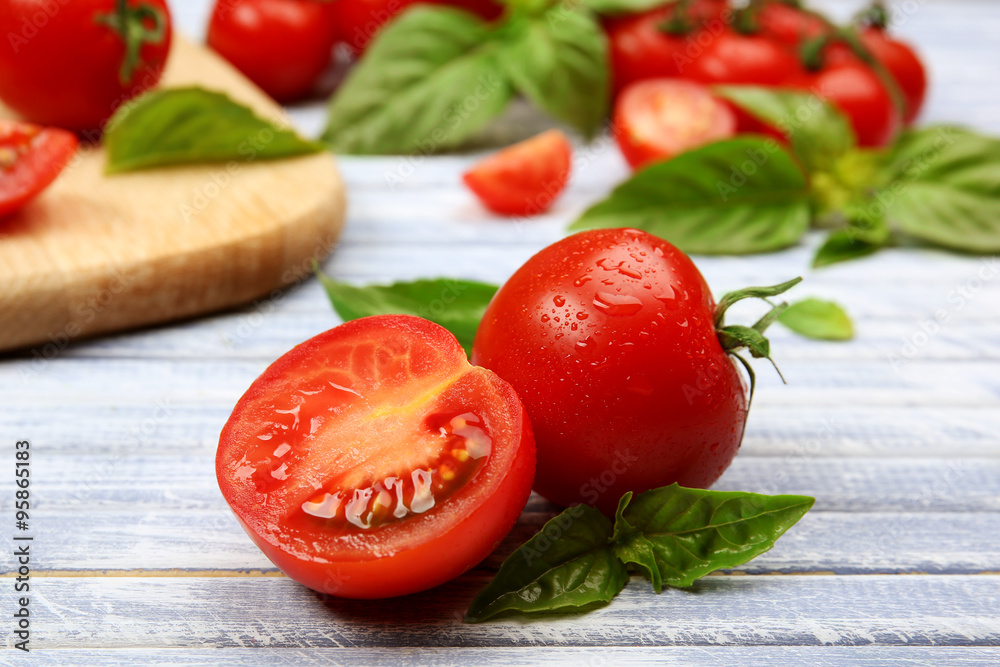 Fresh tomatoes with basil on wooden table close up