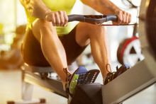 Man Training On Row Machine In Gym
