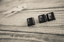 I AM Wrote With Keyboard Keys On Wooden Background, Black And Wh