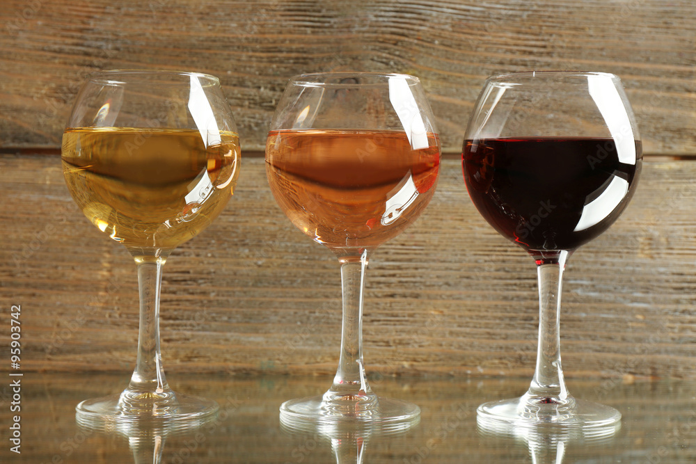 Glasses with white, rose and red wine on wooden background