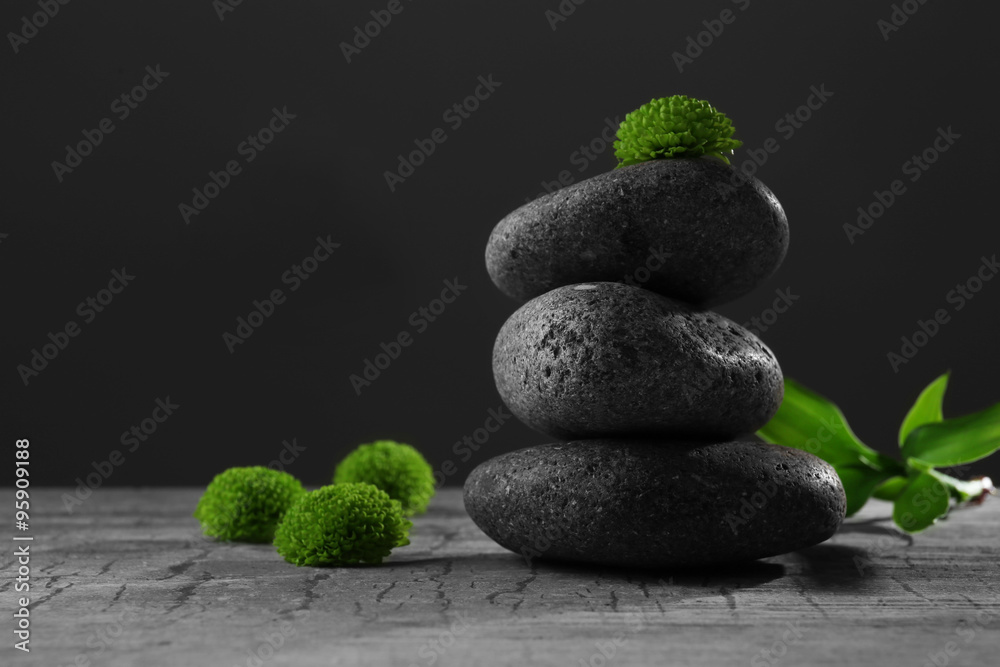 Black spa stones and green flowers, on dark grey background