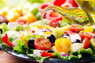 Wall Mural - olive oil pouring into plate of greek salad