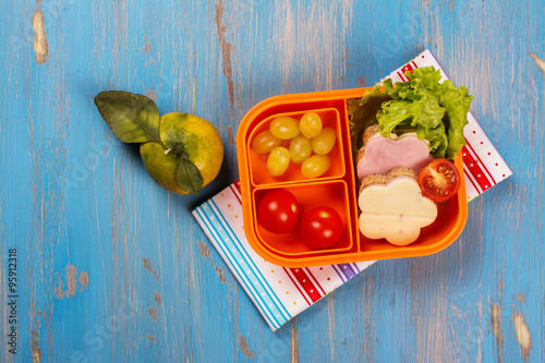 Fototapeta na wymiar School lunch box for kids. Funny flower shaped sandwiches, fruits, vegetables and juice. Selective focus