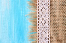 Lace Border On Jute Canvas Cloth And Turquoise Wooden Surface Background. 