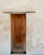 Wooden Door against White Washed Plaster Wall   /  Vertical perspective of an old mission wooden door against a white washed plaster wall