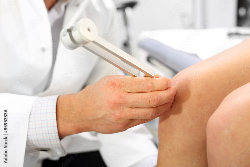 Kamerton, badanie ortopedyczne.Lekarz ortopeda bada kolano pacjenta przy użyciu kamertonu. - obrazy, fototapety, plakaty 
