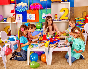 Wall Mural - Children with teacher woman painting on paper in  kindergarten