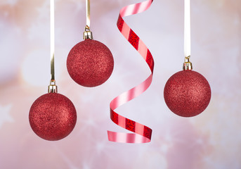 red christmas baubles hanging from ribbon on an abstract colorful background