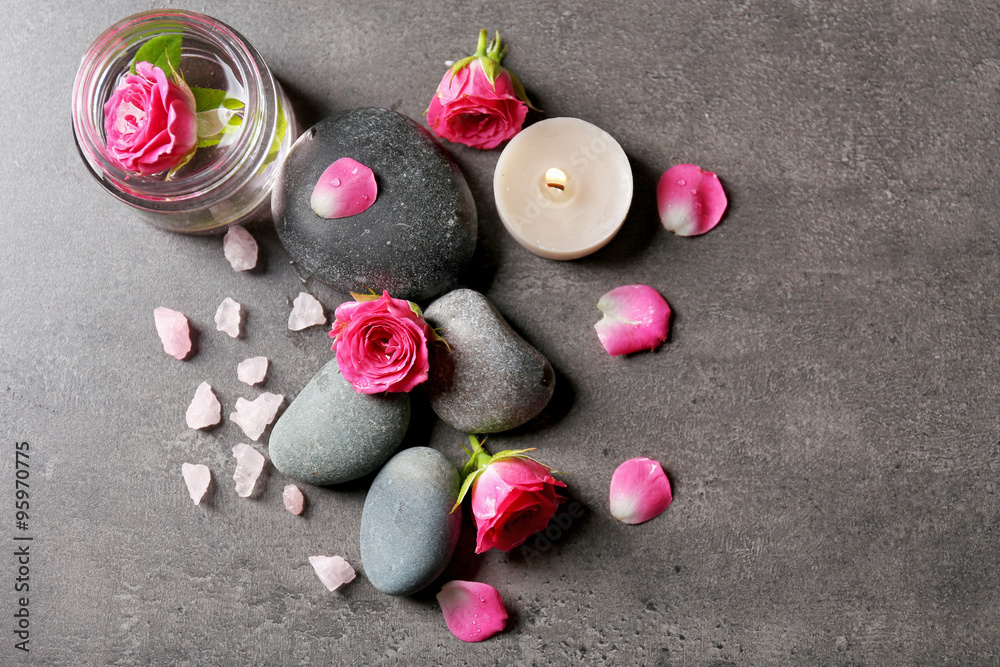 Spa composition of candles,  stones and flowers, on grey background