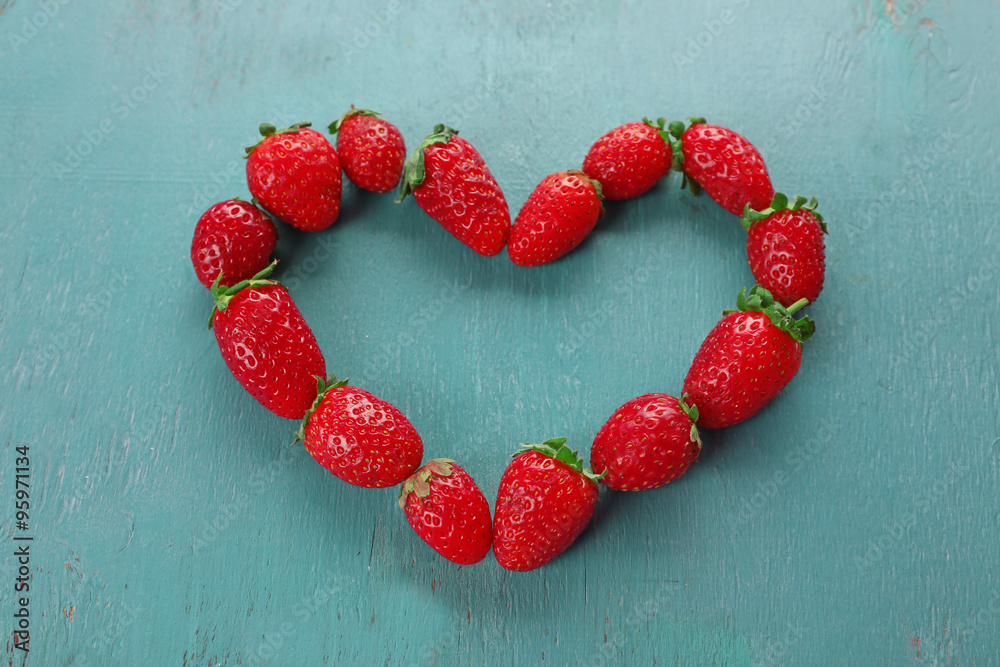 Heart shaped strawberries on blue wooden background