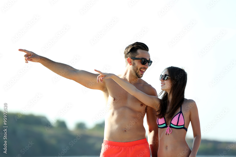 Happy couple pointing at the beach, outdoors