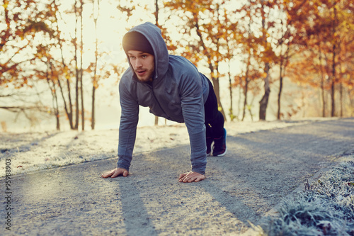 Fotografie, Obraz Young runner doing push ups exercise during cold autumn morning