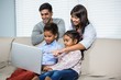 © WavebreakmediaMicro - Smiling family using laptop on the sofa