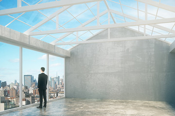 Aufkleber - Businessman in empty loft interior room with city view, grey wal