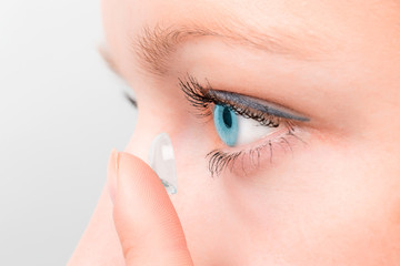 Wall Mural - Woman inserting a contact lens in eye.