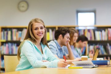 Poster - happy student girl writing to notebook in library