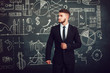 © kanashkin - A bearded man in a suit standing near whiteboard with graphs