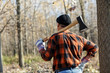 Rearview of senior lumberjack in nature holding an axe on his shoulder