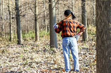 Wall Mural - Rearview of senior lumberjack in nature holding an axe on his shoulder