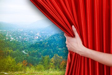 Wall Mural - Human hand opens red curtain on nature background