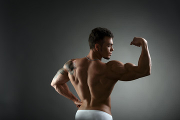 Wall Mural - rear view of tattooed bodybuilder showing biceps