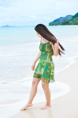 Beautiful teen girl dipping toes in water on tropical beach