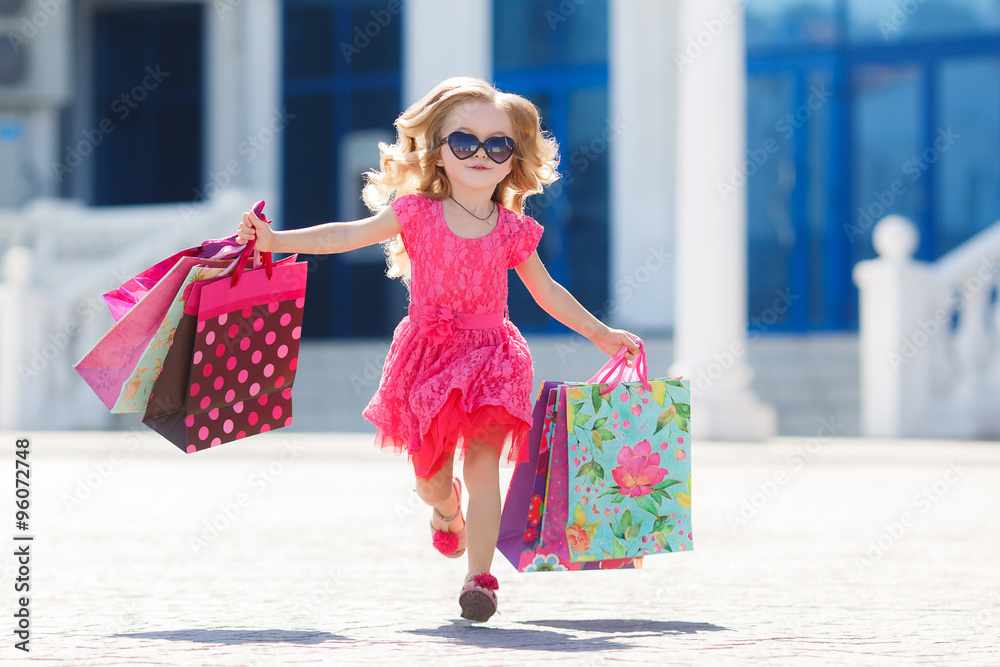 Foto de Stock Little girl with shopping bags goes to the store | Adobe Stock