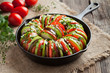 Raw vegetable ratatouille in cast iron frying pan preparation recipe on vintage wooden table background. Healthy organic vegan oven baked food