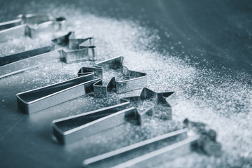  shaped cookie cutters and flour on dark blue table