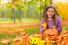 Girl Sits With Pumpkin In The Autumn Forest