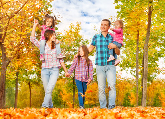 Wall Mural - Family walk in the autumn park holding hands