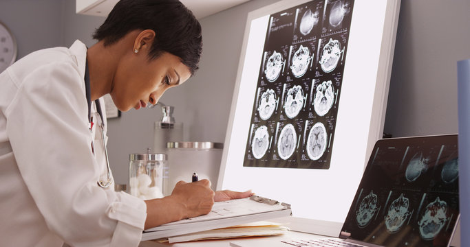Wall Mural -  - African medical woman reading x-ray results of a brain