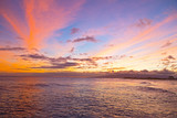 Fototapeta Most - Sunset on a surfing beach in Honolulu, Hawaii. Tropical beach at sunset with surfers and boats.