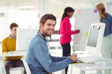 Wall Mural - Graphic designer wearing headphones at desk