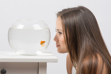 Wall Mural - Young girl leaning face to the aquarium and looking at goldfish